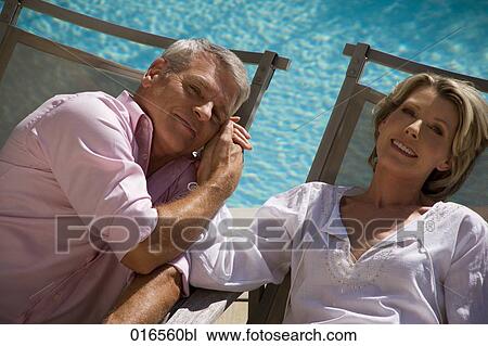 Stock Image - headshot of mature couple on sun loungers. Fotosearch