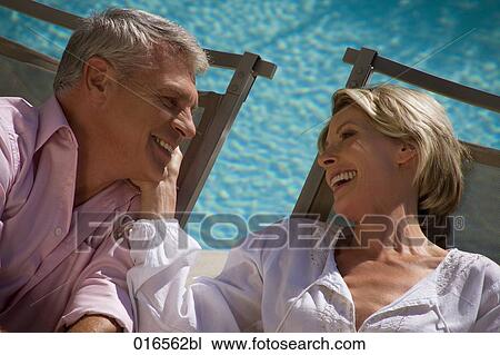 Stock Image - headshot of mature couple on sun loungers. Fotosearch