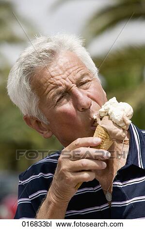 Stock Image - headshot of mature male licking ice cream. Fotosearch