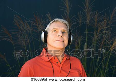 headshot of mature man wearing red shirt listening to music on headphones View Large Photo Image Stock Image - headshot of mature man wearing red shirt listening to music on headphones. Fotosearch