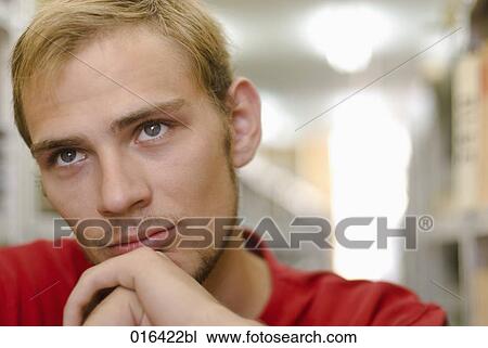 Stock Image - headshot of pensive male student in school library. Fotosearch
