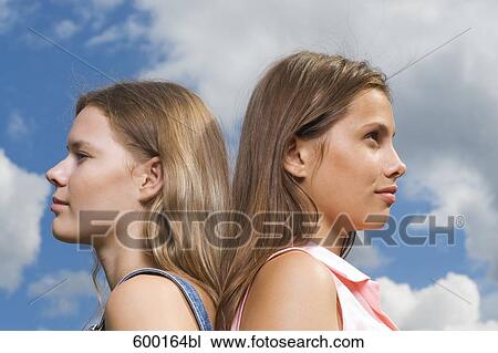 Stock Image - headshot of two young women standing back to back. Fotosearch