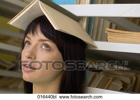 headshot of young female student balancing textbook on her head View Large Photo Image Stock Image - headshot of young female student balancing textbook on her head. Fotosearch