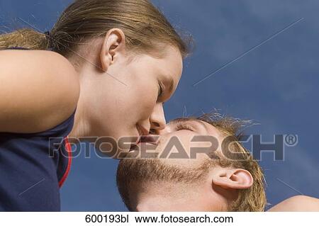Stock Image - low angle portrait of young couple kissing. Fotosearch
