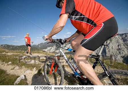 man on mountain bike and woman doing nordic walking meeting in the mountains View Large Photo Image Stock Image - man on mountain bike and woman doing nordic walking meeting in the mountains. Fotosearch