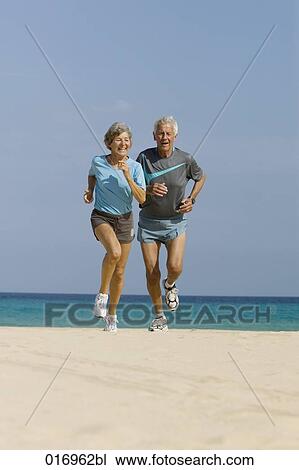 mature couple jogging together on sandy beach View Large Photo Image Stock Image - mature couple jogging together on sandy beach. Fotosearch