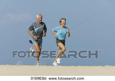 mature couple jogging together on sandy beach View Large Photo Image Stock Image - mature couple jogging together on sandy beach. Fotosearch