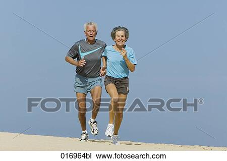 mature couple jogging together on sandy beach View Large Photo Image Stock Image - mature couple jogging together on sandy beach. Fotosearch