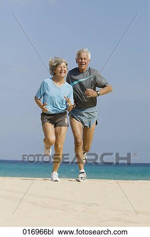 mature couple jogging together on sandy beach View Large Photo Image Stock Image - mature couple jogging together on sandy beach. Fotosearch