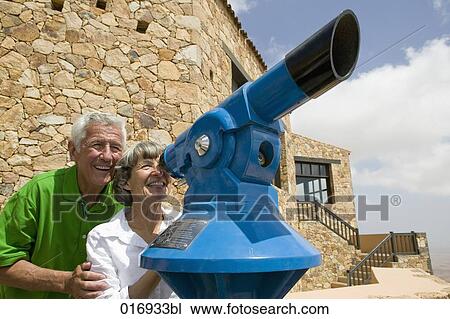 Stock Image - mature couple looking through binocular. Fotosearch
