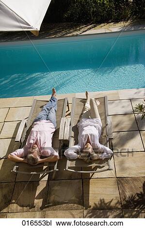 mature couple lying on sun loungers near swimming pool View Large Photo Image Stock Image - mature couple lying on sun loungers near swimming pool. Fotosearch