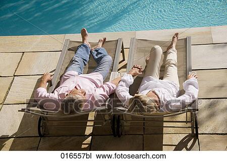 mature couple lying on sun loungers near swimming pool View Large Photo Image Stock Image - mature couple lying on sun loungers near swimming pool. Fotosearch