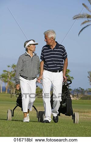 mature couple pulling golf bags over golf course View Large Photo Image Stock Image - mature couple pulling golf bags over golf course. Fotosearch