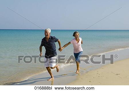 mature couple running along beach hand in hand View Large Photo Image Stock Image - mature couple running along beach hand in hand. Fotosearch