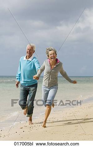 mature couple running hand in hand on beach View Large Photo Image Stock Image - mature couple running hand in hand on beach. Fotosearch