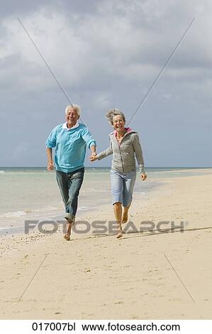 mature couple running hand in hand on beach View Large Photo Image Stock Image - mature couple running hand in hand on beach. Fotosearch