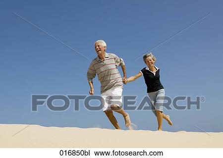 mature couple running on beach hand in hand View Large Photo Image Stock Image - mature couple running on beach hand in hand. Fotosearch