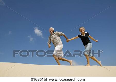 mature couple running on beach hand in hand View Large Photo Image Stock Image - mature couple running on beach hand in hand. Fotosearch