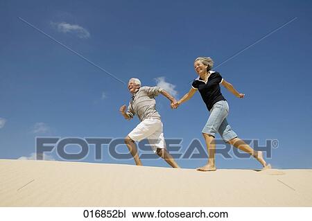 mature couple running on beach hand in hand View Large Photo Image Stock Image - mature couple running on beach hand in hand. Fotosearch