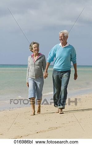 mature couple walking hand in hand along beach View Large Photo Image Stock Image - mature couple walking hand in hand along beach. Fotosearch