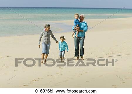 mature couple with their grandchildren having a walk along the beach View Large Photo Image Stock Image - mature couple with their grandchildren having a walk along the beach. Fotosearch