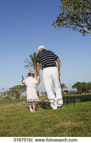 Stock Image - mature golf player and grandchild on golf course. Fotosearch