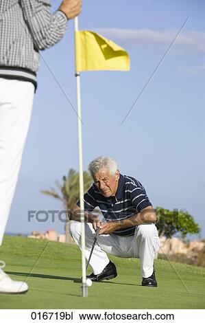 mature golf player kneeling by hole on puuting green View Large Photo Image Stock Image - mature golf player kneeling by hole on puuting green. Fotosearch