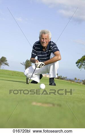 mature golf player kneeling by hole on puuting green View Large Photo Image Stock Image - mature golf player kneeling by hole on puuting green. Fotosearch