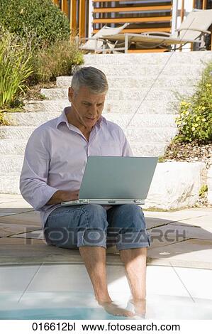 mature man sitting at swimming pool and working with laptop computer View Large Photo Image Stock Image - mature man sitting at swimming pool and working with laptop computer. Fotosearch