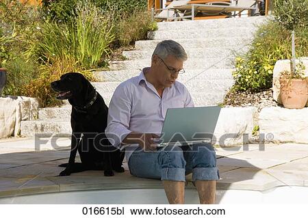 mature man sitting at swimming pool with dog and working with laptop computer View Large Photo Image Stock Image - mature man sitting at swimming pool with dog and working with laptop computer. Fotosearch
