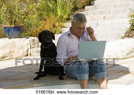 mature man sitting at swimming pool with dog and working with laptop computer View Large Photo Image Stock Image - mature man sitting at swimming pool with dog and working with laptop computer. Fotosearch