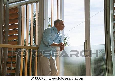 mature man standing in living room looking out of window View Large Photo Image Stock Image - mature man standing in living room looking out of window . Fotosearch