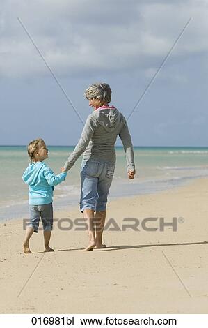 mature woman and granddaughter walking along beach View Large Photo Image Stock Image - mature woman and granddaughter walking along beach. Fotosearch