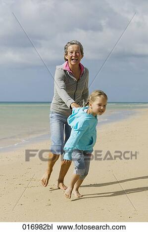 mature woman and granddaughter walking along beach View Large Photo Image Stock Image - mature woman and granddaughter walking along beach. Fotosearch