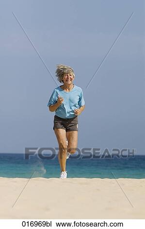 mature woman jogging on sandy beach View Large Photo Image Stock Image - mature woman jogging on sandy beach. Fotosearch