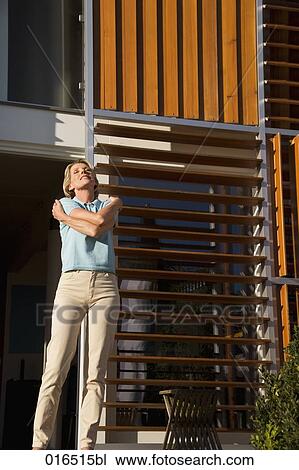 mature woman standing in front of her home enjoying the first rays of sun View Large Photo Image Stock Image - mature woman standing in front of her home enjoying the first rays of sun. Fotosearch