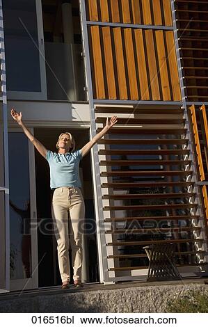 mature woman standing in front of her home enjoying the first rays of sun View Large Photo Image Stock Image - mature woman standing in front of her home enjoying the first rays of sun. Fotosearch
