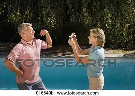 mature woman taking portrait of husband with digital camera in front of swimming pool View Large Photo Image Stock Image - mature woman taking portrait of husband with digital camera in front of swimming pool. Fotosearch
