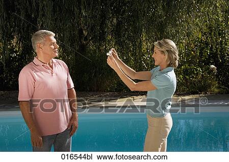mature woman taking portrait of husband with digital camera in front of swimming pool View Large Photo Image Stock Image - mature woman taking portrait of husband with digital camera in front of swimming pool. Fotosearch