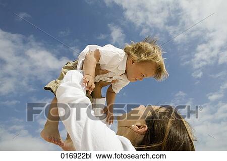mother holding her young son up in the air View Large Photo Image Stock Image - mother holding her young son up in the air. Fotosearch