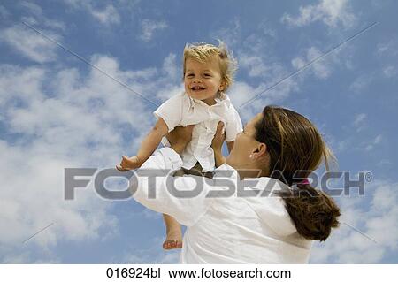 mother holding her young son up in the air View Large Photo Image Stock Image - mother holding her young son up in the air. Fotosearch