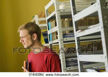 pensive student standing at bookshelf in library View Large Photo Image Stock Image - pensive student standing at bookshelf in library. Fotosearch
