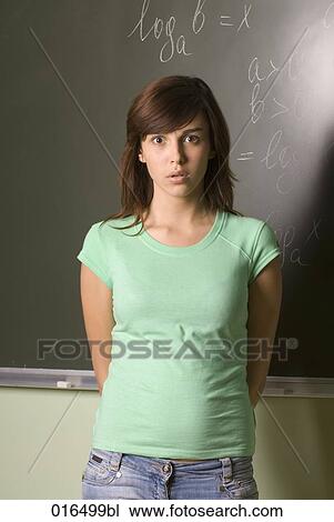 Stock Image - portrait of confused female student standing in front of blackboard. Fotosearch