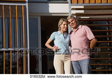 portrait of mature couple standing in front of home View Large Photo Image Stock Image - portrait of mature couple standing in front of home. Fotosearch
