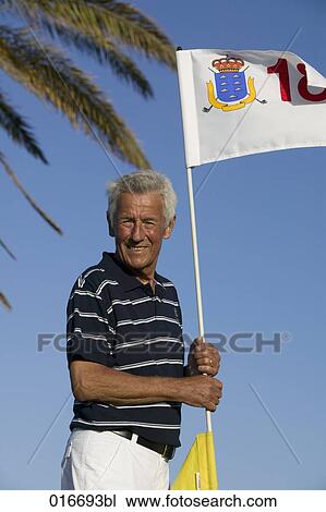Stock Image - portrait of mature golf player holding flag. Fotosearch
