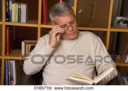 Stock Image - portrait of mature man with spectacles reading a book. Fotosearch