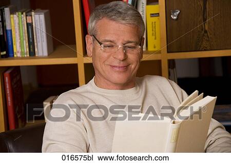 Stock Image - portrait of mature man with spectacles reading a book. Fotosearch