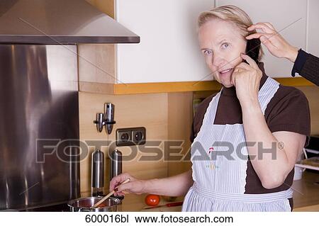 portrait of mature woman cooking in kitchen and talking on mobile phone View Large Photo Image Stock Image - portrait of mature woman cooking in kitchen and talking on mobile phone. Fotosearch