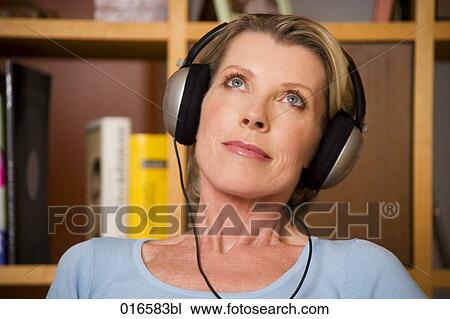 Stock Image - portrait of mature woman listening to music with headphones. Fotosearch