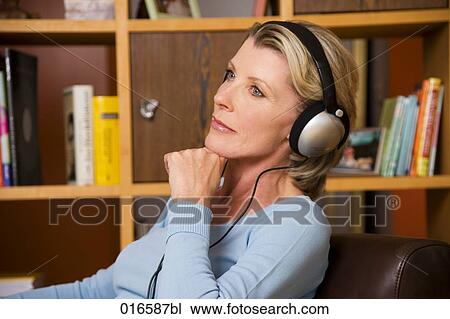 Stock Image - portrait of mature woman listening to music with headphones. Fotosearch
